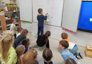 Dzieci graja z misiem w wyscigi magnesami na tablicy