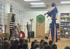 03 Chłopiec rzuca obręcz do artystki na szczudłach