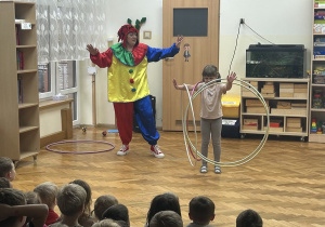 10 Dziewczynka w towarzystwie artystki w stroju klauna kręci obręczami