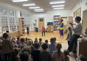 16 Dziewczynka przeskakuje przez linę trzymaną przez chłopca i artystkę