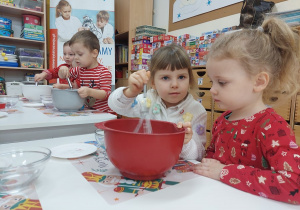 14. Dziewczynka miesza trzepaczką w misce.