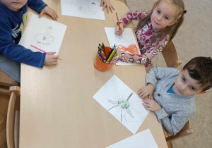 Dzieci rysują i malują na kartkach bakterie i zarazki.