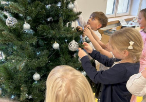 Dzieci pokolei przywieszaja bombki