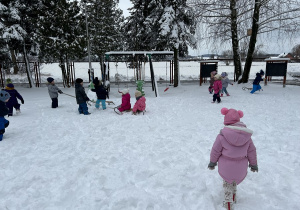 Dzieci wesoło bawią się na śniegu.