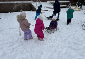 Dzieci wesoło bawią się na śniegu.