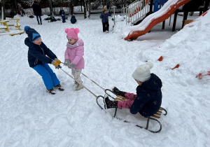 Dzieci wesoło bawią się na śniegu.