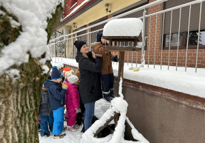 Przedszkolaki dosypują nasiona do karmnika.