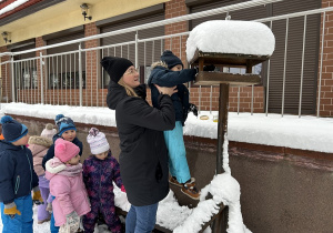 Przedszkolaki dosypują nasiona do karmnika.