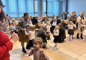 36. Dziadkowie i dzieci bawią się do muzyki.