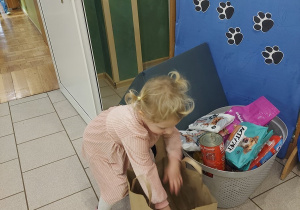 Dziewczynka wykłada przyniesione psie przysmaki.