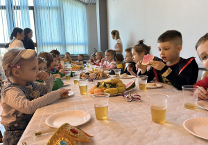 33 Dzieci przy stolikach jedzą owoce i słodycze