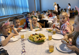 34 Dzieci przy stolikach jedzą owoce i słodycze