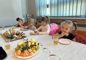 35 Dziewczynki przy stoliku jedzą owoce i słodycze