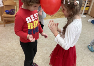 Dzieci trzymają balon główkami.