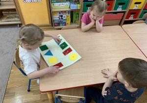 Dziewczynka łączy takie same figury geometryczne.