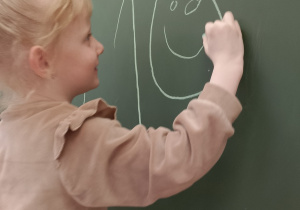 Dziewczynka zapisuje na tablicy liczbę 10.