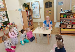 Nauczycielka przedstawia dzieciom deszczomierz.