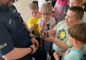 Policjant zakłada przedszkolakowi kajdanki