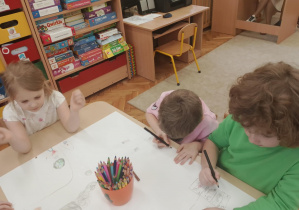 Dzieci pracują w grupach nad plakatem.