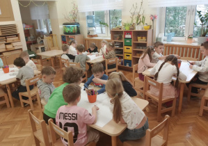 Dzieci pracują w grupach nad plakatem.