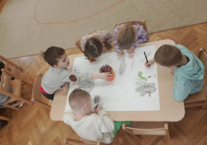 Dzieci pracują wspólnie nad plakatem.