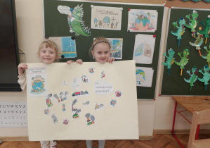 Dziewczynki prezentują plakat o zanieczyszczeniach powietrza.
