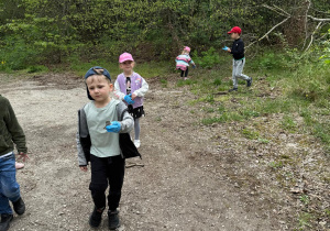 Dzieci zbierają śmieci koło lasu.