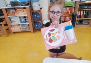 Dziewczynka pokazuje swoją pracę plastyczną