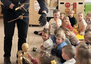 05 Dzieci siedzące na dywanie przybijają piątkę z marionetką poruszaną przez artystę