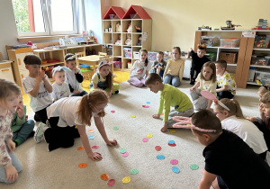 01 Chłopiec i dziewczynka odszukują obrazki na papierowych kolorowych jajeczkach lezących na dywanie