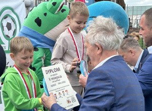 Chłopcy z grupy pięciolatków odbierają medale i dyplomy stojąc na podium.