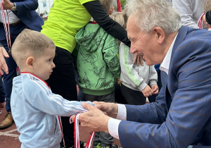 13 Chłopiec z grupy trzylatków przyjmuje medal i gratulacje za ukończenie biegu.