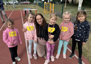 21 Dziewczynki z grupy pięciolatków pozują ze swoimi medalami i nauczycielką.