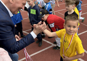 30 Chłopiec przybija piątkę z panem wręczającym mu medal.