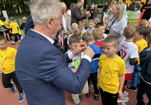 31 Pan zakłada chłopcu medal za ukończenie biegu.