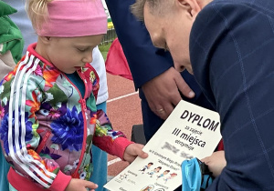 40 Dziewczynka z grupy trzylatków odbiera dyplom i brązowy medal.