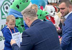 44 Chłopiec z grupy czterolatków na podium odbiera dyplom i medal.