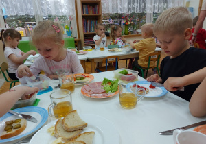 Radosne przedszkolaki układają składniki na kanapkach.