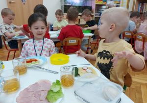 Zadowolone przedszkolaki oglądają swoje kanapki.