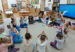 Przedszkolaki wraz z nauczycielem wykonują ćwiczenie.
