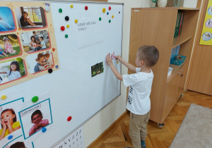 Chłopiec przeyczepia na tablicy ilustrację prezentującą miejsce, gdzie można znaleźć ciszę.