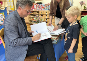 08 Autor podpisuje książkę dla stojącego przed nim chłopca.