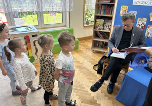 10 Dzieci czekają w kolejce na podpisanie książki przez autora.