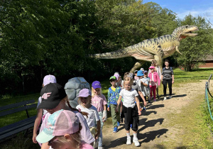 Dzieci zwiedzają ścieżkę pełną dinozaurów.