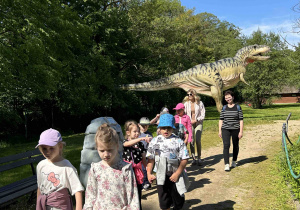 Dzieci zwiedzają ścieżkę pełną dinozaurów.