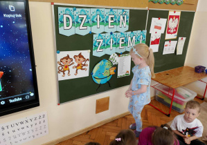 Dziewczynka stoi koło tablicy.