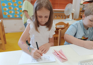 Dziewczynka rysuje monety na kartce