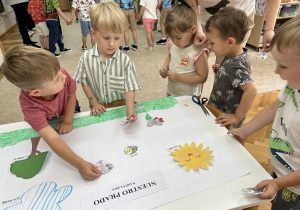 Chłopcy przyklejają pokolorowane ilustracje.