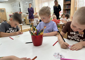 Przedszkolaki kolorują biedronki i pszczółki.