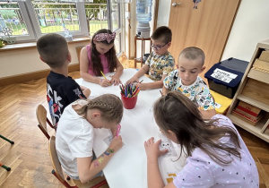 Sześciolatki kolorują obrazki ze zwierzątkami.